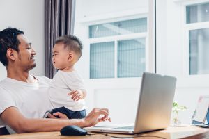 Man father using working on laptop computer with son in home